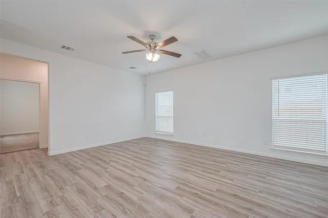 a view of empty room with wooden floor and fan