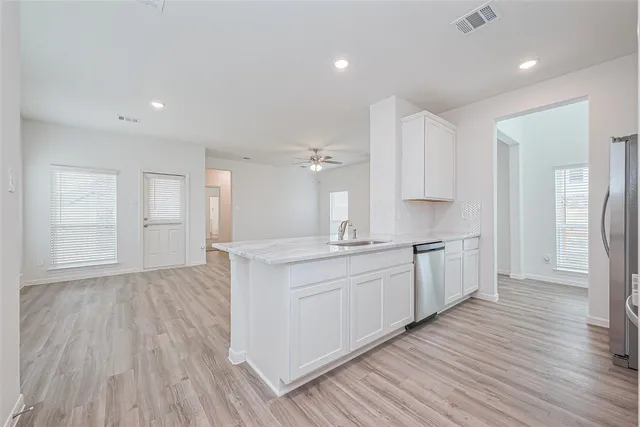 a large kitchen with cabinets wooden floor and stainless steel appliances