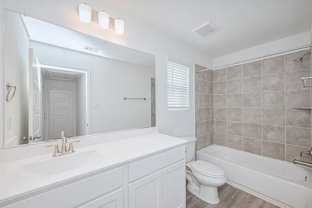 a bathroom with a bathtub shower sink vanity mirror and toilet