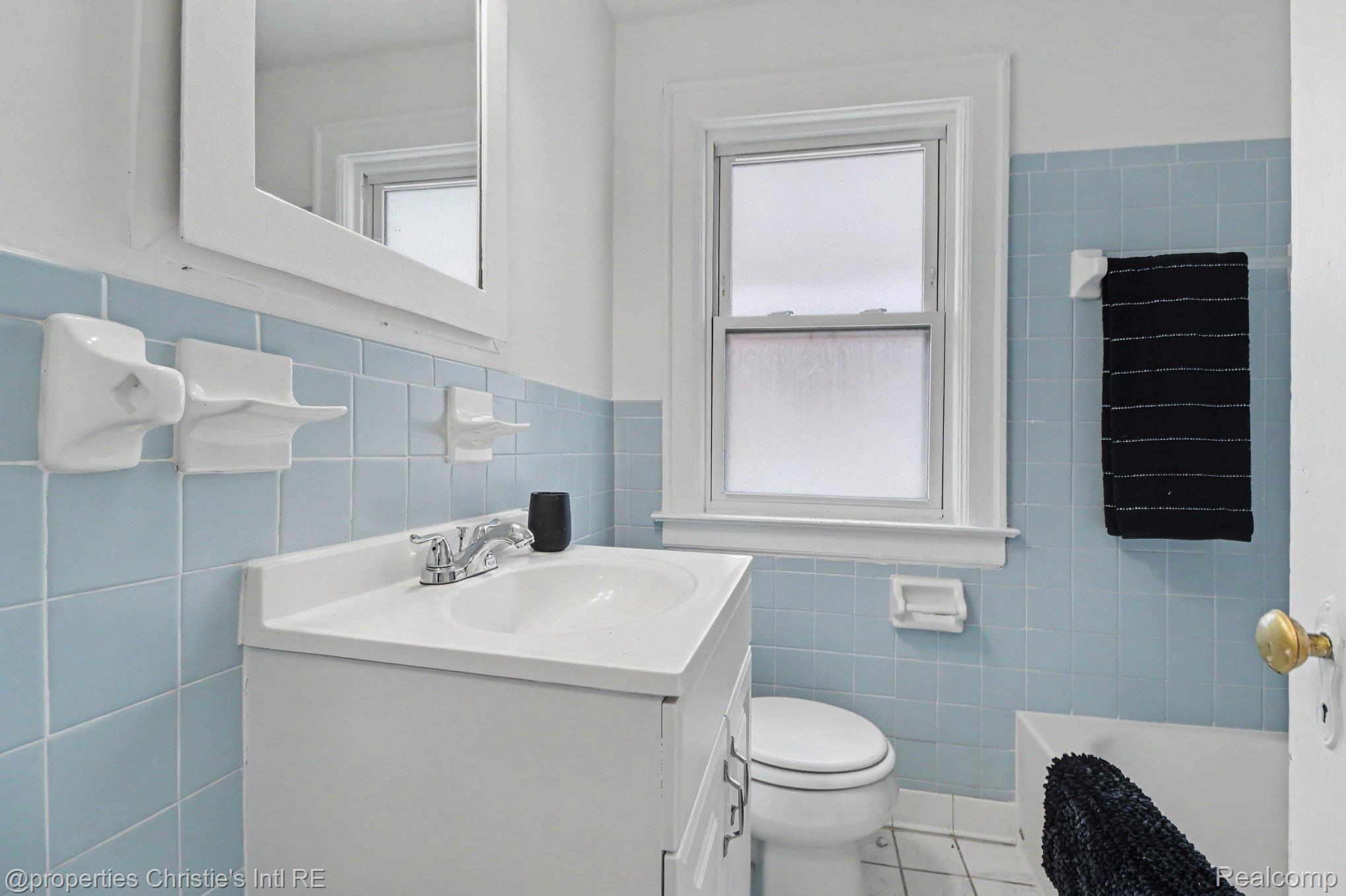 18315 Prairie Street Detroit, MI 48221 - Photo 11 of 16 Bathroom featuring a white vanity with integrated sink, chrome faucet, and a window with frosted glass