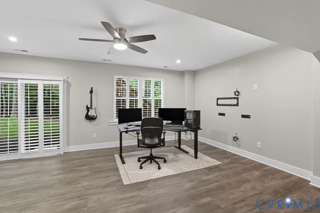 a workspace with furniture a ceiling fan and wooden floor
