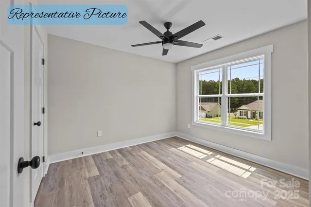 an empty room with wooden floor a ceiling fan and windows