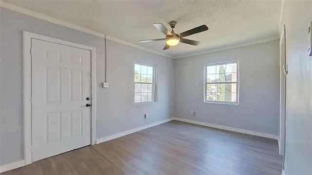 an empty room with wooden floor closet and windows
