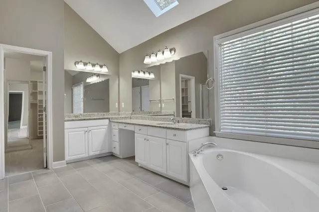 a bathroom with a granite countertop sink a large mirror and a bathtub