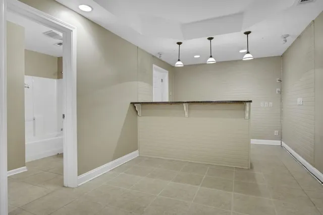 an empty room with kitchen view and wooden floor