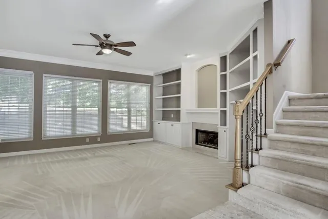 a view of an empty room with wooden floor fireplace and a window