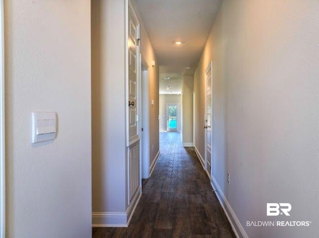 16810 Rocher Court Foley, AL 36535 - Photo 23 of 24 Long hallway featuring wood-finish flooring, light neutral wall tones, white baseboards, recessed lighting, and white paneled doors