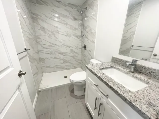 a bathroom with a granite countertop toilet a sink and a mirror