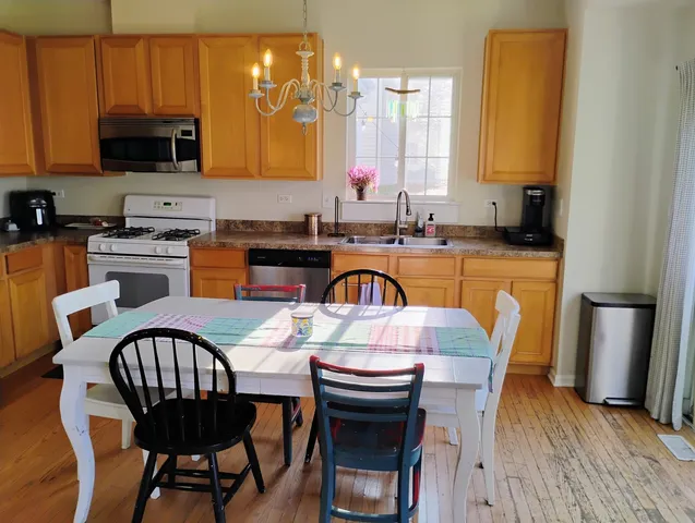 a kitchen with granite countertop wooden floors a stove a sink a dining table and chairs