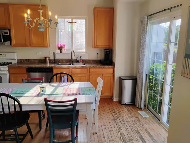 a kitchen with stainless steel appliances granite countertop a table chairs sink and cabinets