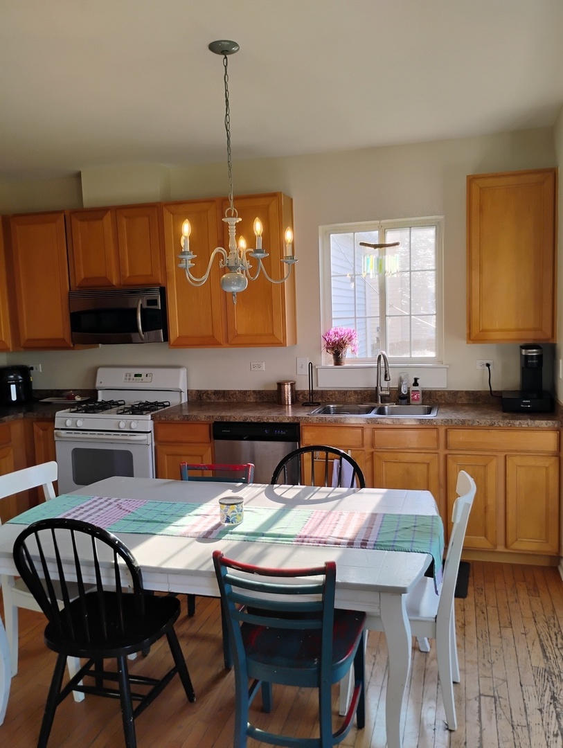178 West Hampton Drive Round Lake, IL 60073 - Photo 6 of 55 a kitchen with stainless steel appliances granite countertop a stove a sink dishwasher a dining table and chairs with wooden floor