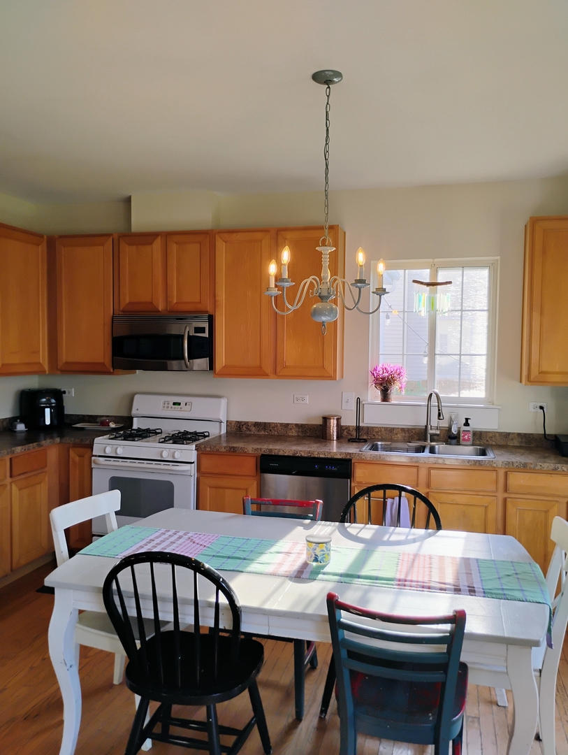 178 West Hampton Drive Round Lake, IL 60073 - Photo 9 of 55 a kitchen with stainless steel appliances granite countertop a stove a sink a microwave a dining table and chairs