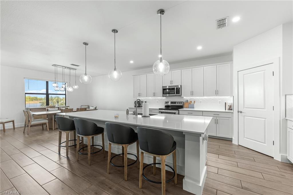 1465 Birdie Drive Naples, FL 34120 - Photo 11 of 38 a kitchen with stainless steel appliances granite countertop a sink a stove a refrigerator and island with wooden floor