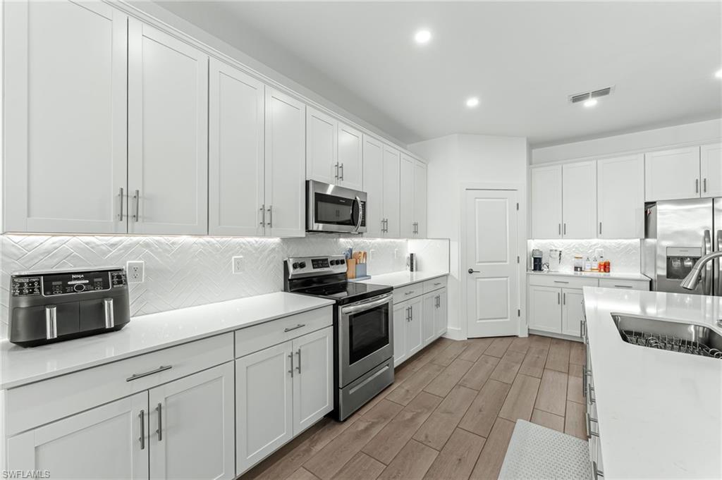 1465 Birdie Drive Naples, FL 34120 - Photo 12 of 38 a kitchen with granite countertop white cabinets and white appliances