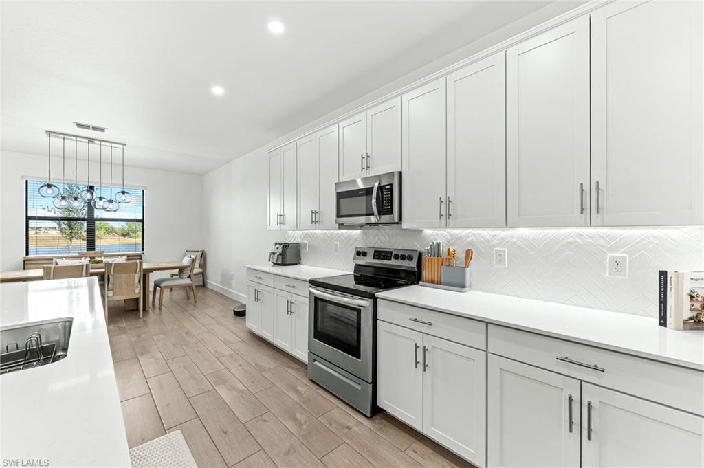 1465 Birdie Drive Naples, FL 34120 - Photo 14 of 38 a kitchen with white cabinets and white appliances