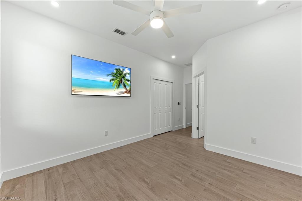 1465 Birdie Drive Naples, FL 34120 - Photo 24 of 38 an empty room with wooden floor chandelier fan and windows