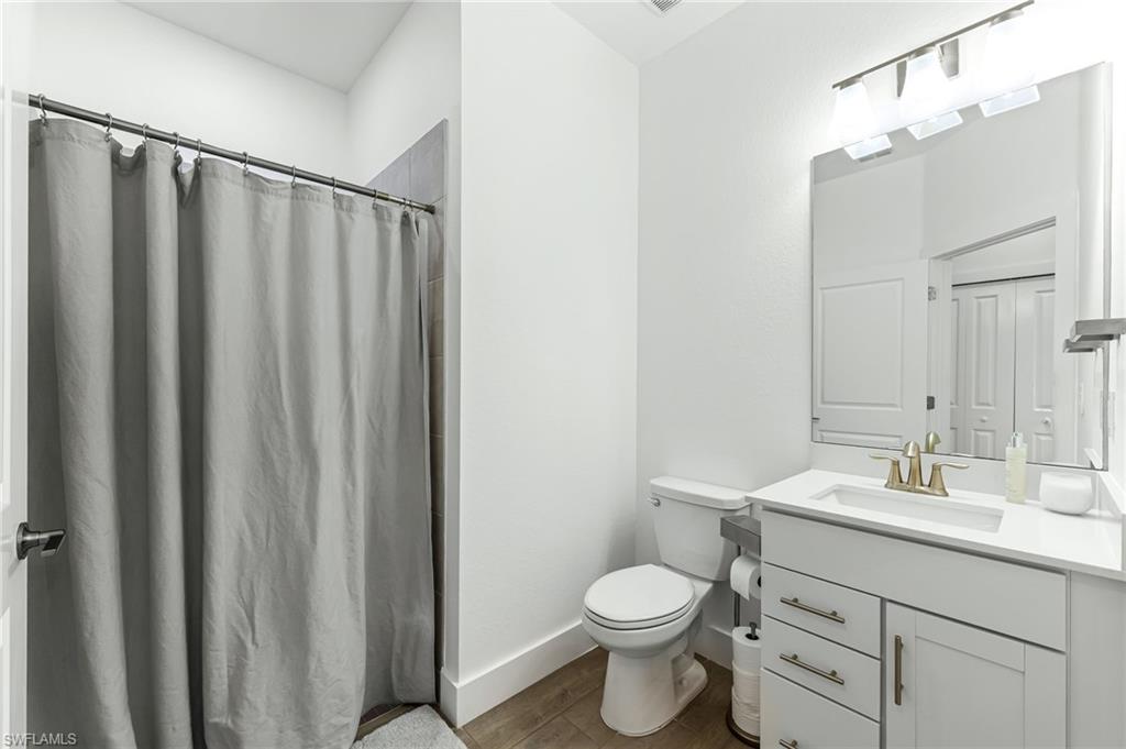 1465 Birdie Drive Naples, FL 34120 - Photo 26 of 38 a bathroom with a sink a toilet a mirror and shower curtain