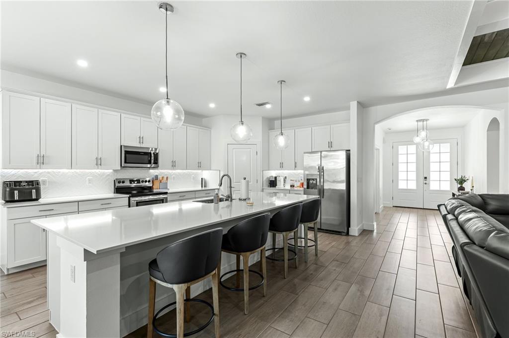 1465 Birdie Drive Naples, FL 34120 - Photo 10 of 38 a kitchen with stainless steel appliances a table and chairs in it