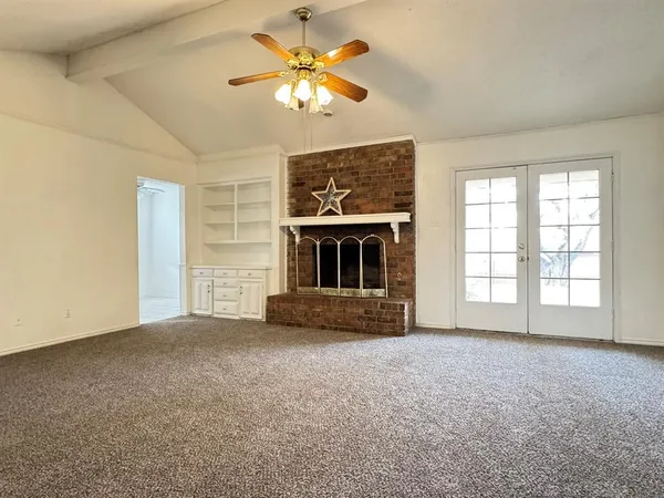 an empty room with fireplace fan and windows
