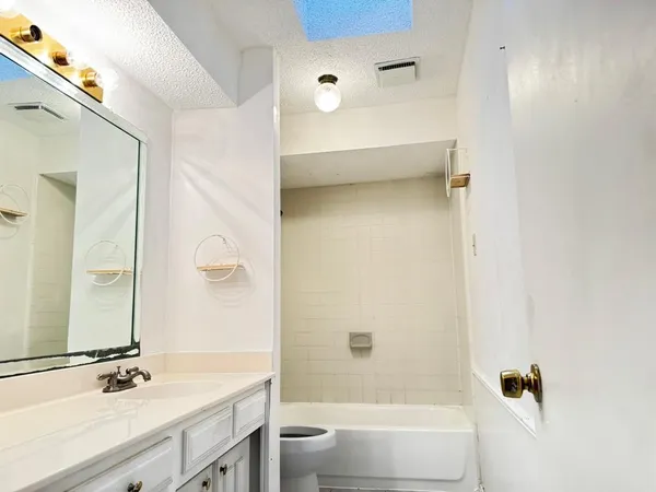 a bathroom with a bathtub shower sink vanity and toilet