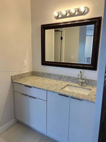 a bathroom with a granite countertop sink and a mirror