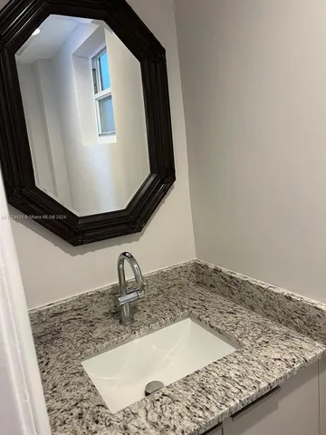 a bathroom with a granite countertop sink and mirror