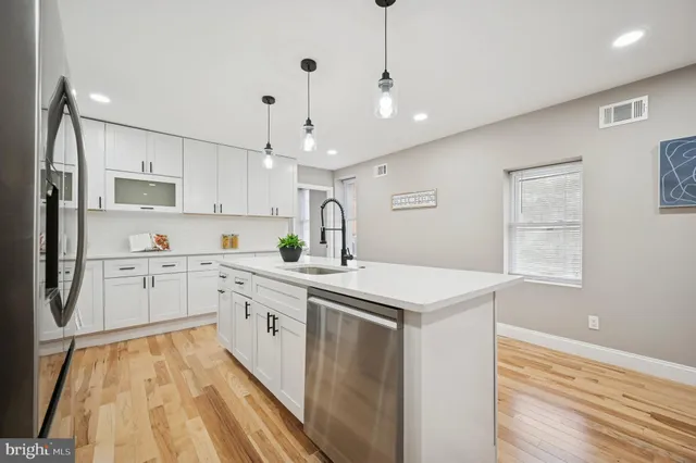 a kitchen that has a lot of white cabinets and wooden floor