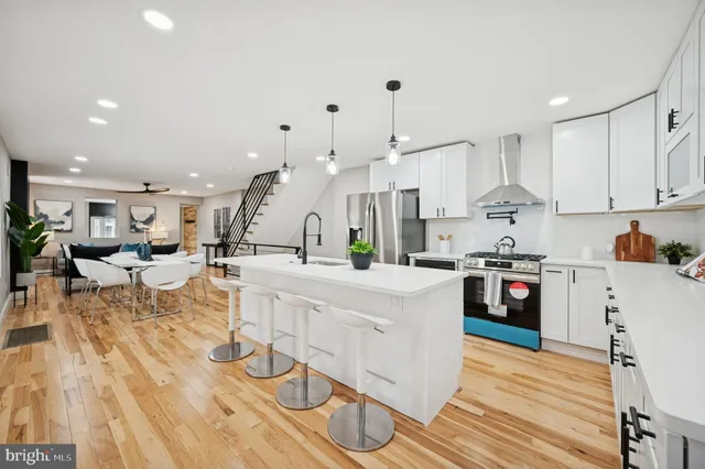 a large white kitchen with lots of counter space wooden floor and appliances