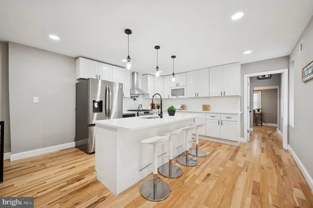 a kitchen with stainless steel appliances a refrigerator a stove and white cabinets with wooden floor