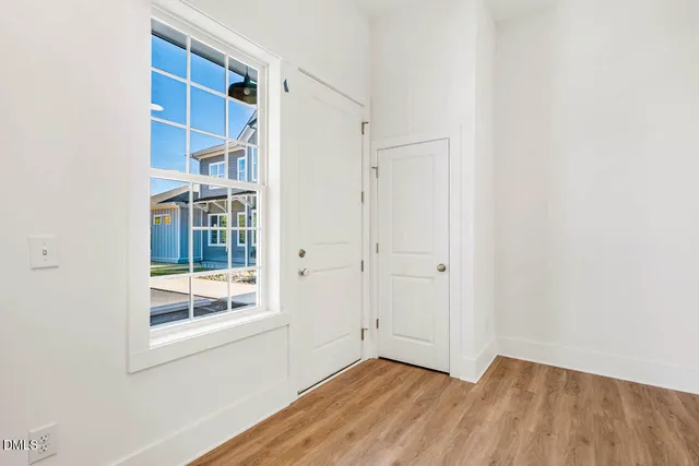 a view of an empty room with wooden floor and a window