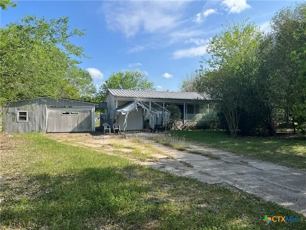 a view of a house with a yard and a large tree