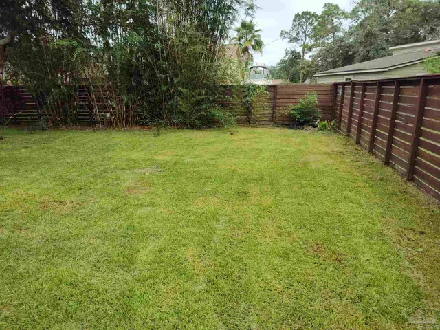 a view of a yard with wooden fence