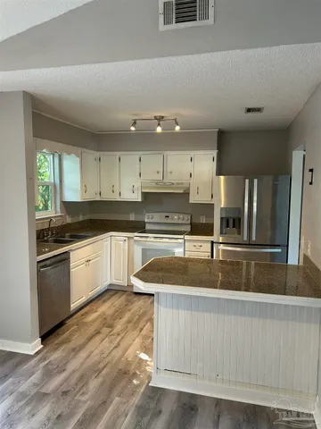 a large kitchen with stainless steel appliances granite countertop a lot of counter space and a sink