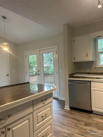 a kitchen with granite countertop a stove and white cabinets with wooden floor