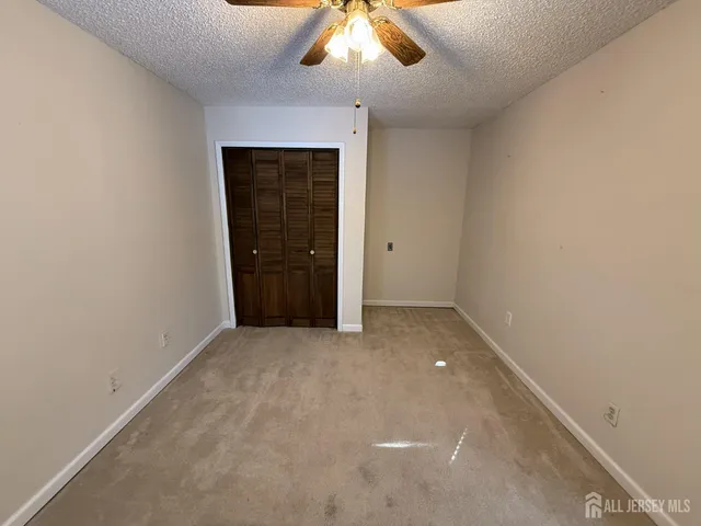 an empty room with a chandelier fan and a window