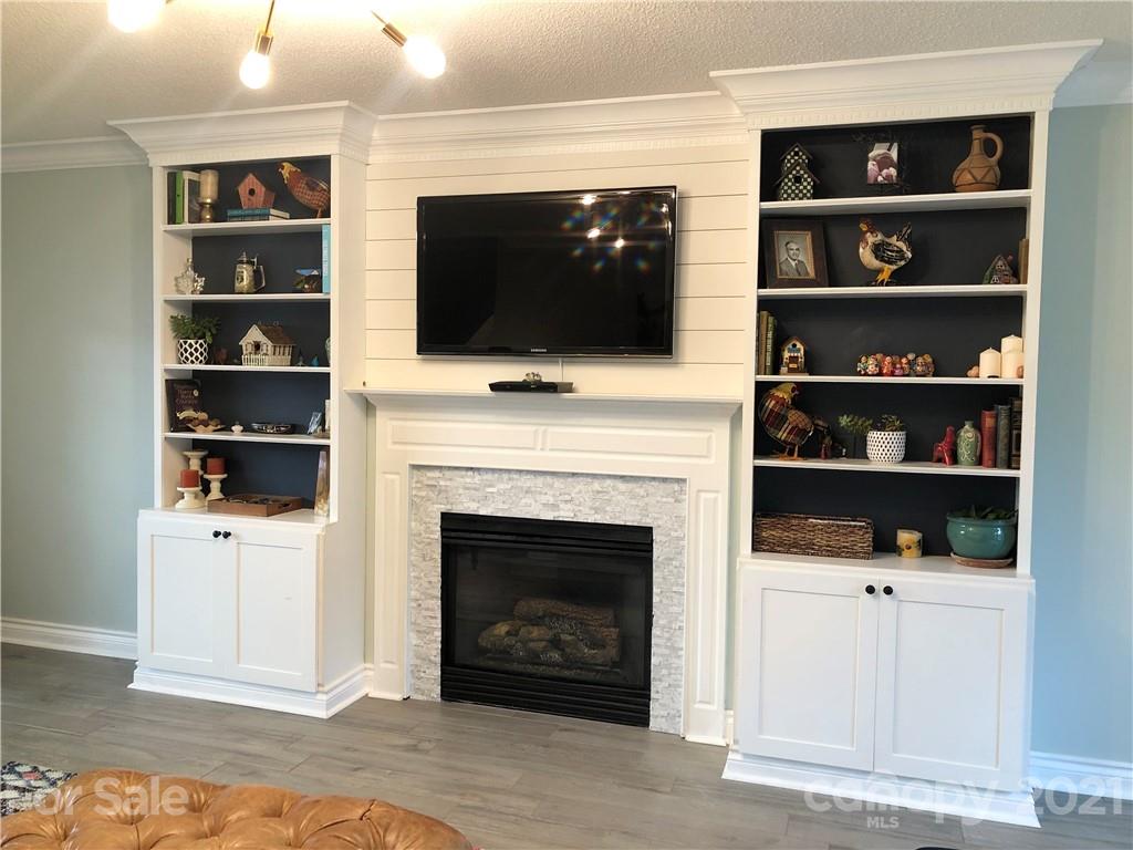 127 Yadkin Road Fletcher, NC 28732 - Photo 10 of 25 a living room with a fireplace a flat screen tv and a book shelf