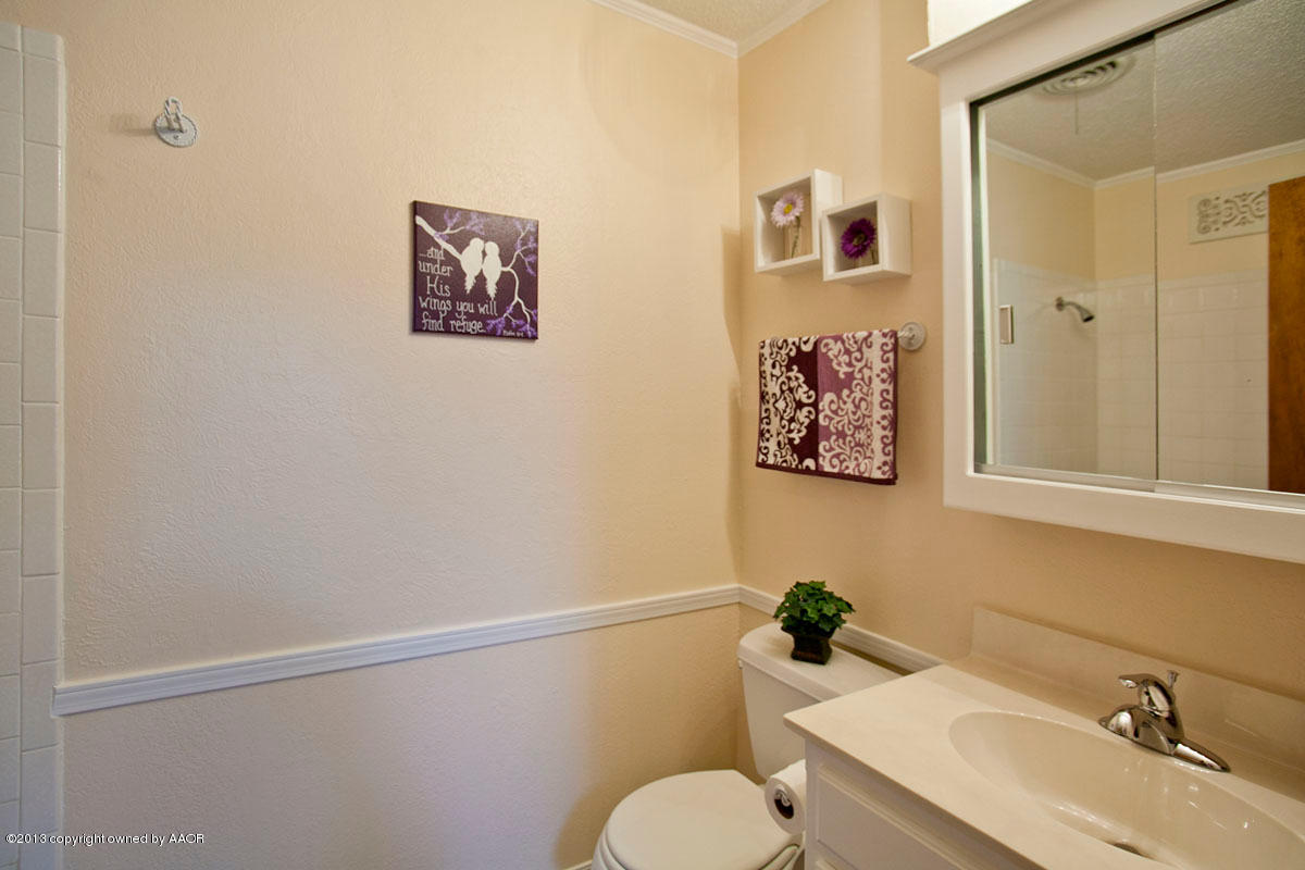 5713 South Milam Street Amarillo, TX 79110 - Photo 14 of 22 a bathroom with a toilet a sink and mirror