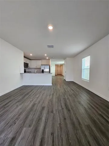 a view of a big room with wooden floor and windows