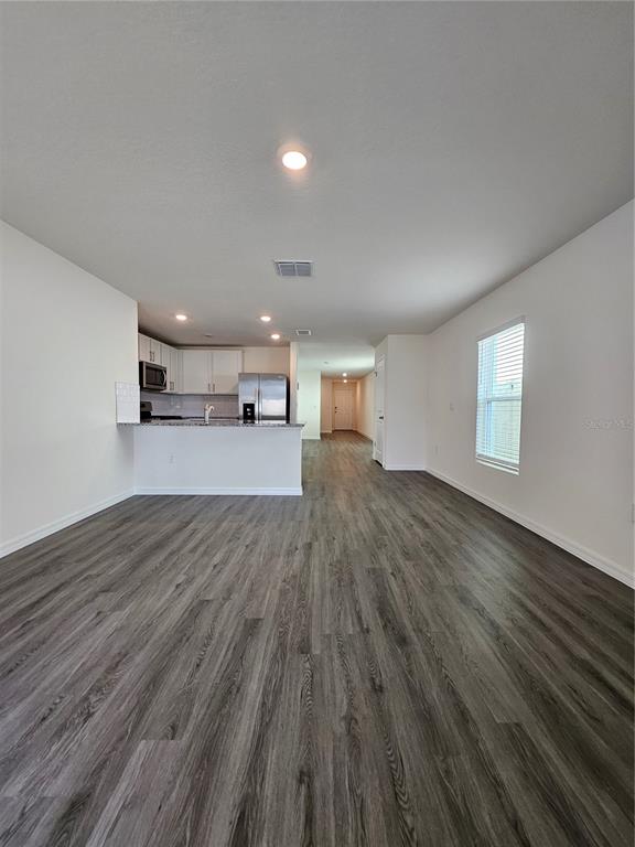 2636 Hardin Way Zephyrhills, FL 33541 - Photo 13 of 42 a view of a big room with wooden floor and windows