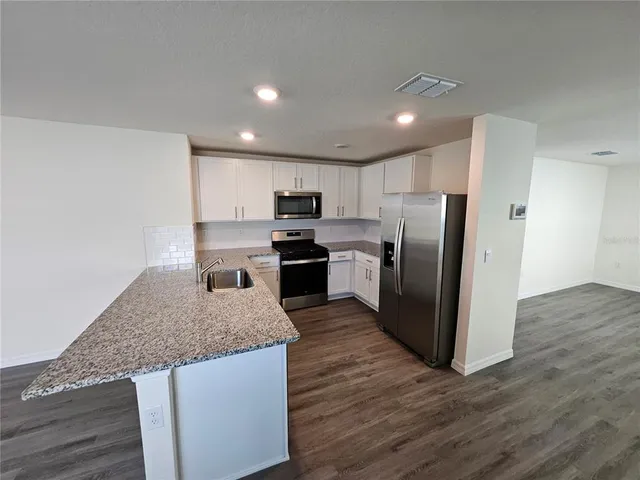 a kitchen with granite countertop a refrigerator and wooden cabinets