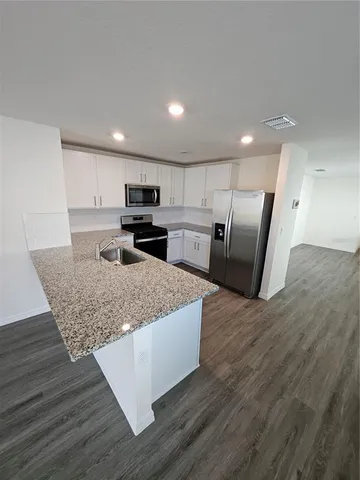a kitchen with stainless steel appliances granite countertop a wooden cabinets a stove and a sink