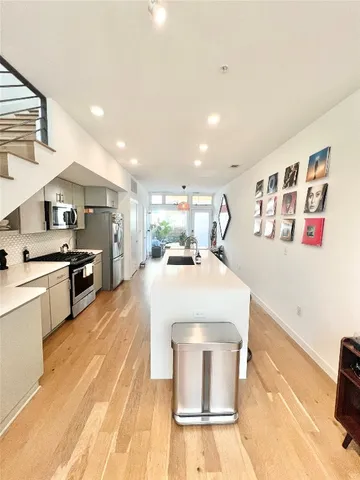 a large kitchen with kitchen island a stove a sink dishwasher and white cabinets with wooden floor