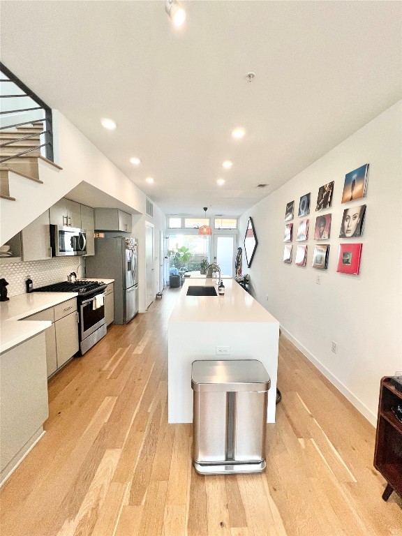 2002 East 7th Street, Unit 223 Austin, TX 78702 - Photo 2 of 14 a large kitchen with kitchen island a stove a sink dishwasher and white cabinets with wooden floor