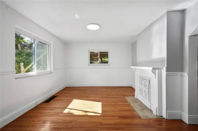 a view of empty room with wooden floor and fan