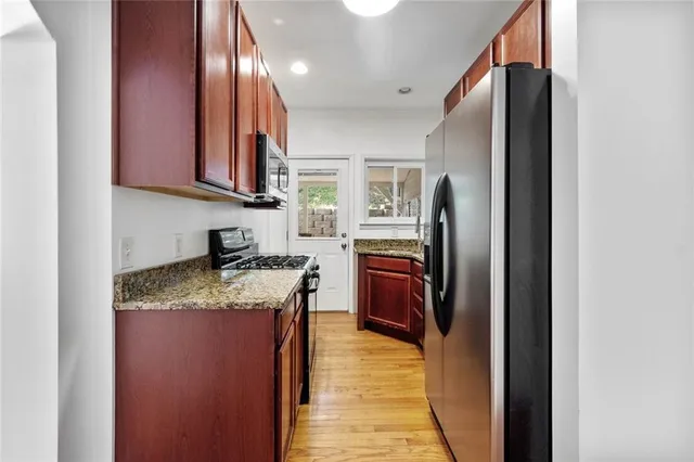 a kitchen with stainless steel appliances granite countertop a refrigerator a stove and a sink