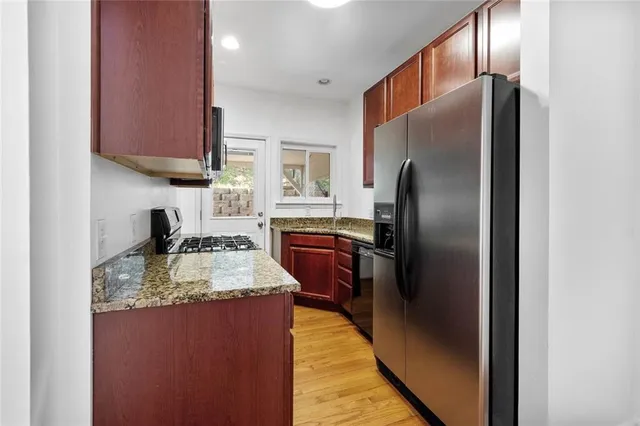 a kitchen with kitchen island granite countertop wooden cabinets a refrigerator and a sink