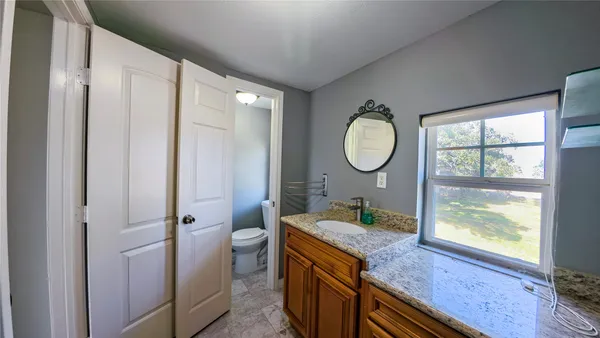 a bath room with a granite countertop toilet sink and a mirror