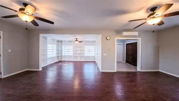 a view of an empty room with a window and wooden floor