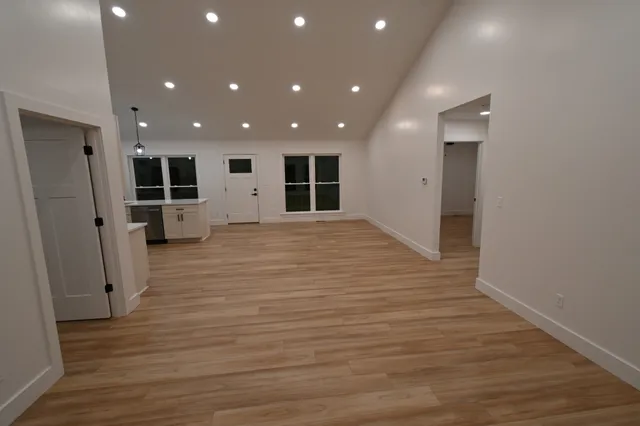an empty room with wooden floor and windows