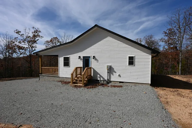 a view of a house with a small yard and a large tree